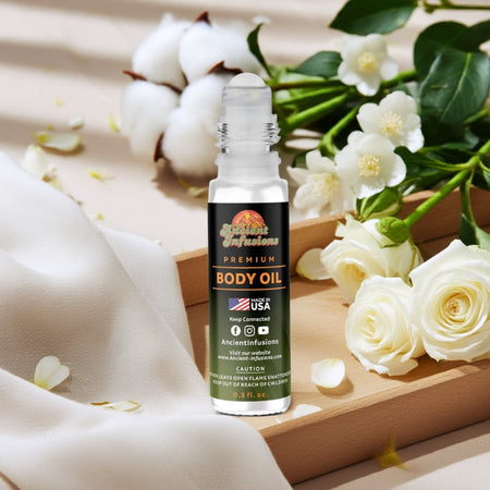 White Linen inspired body oil standing upright on wood platform with white florals and soft cotton accents