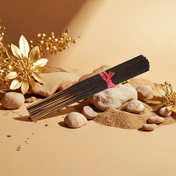 Egyptian Musk Incense Sticks with a red label on a sandy surface with rocks and flowers