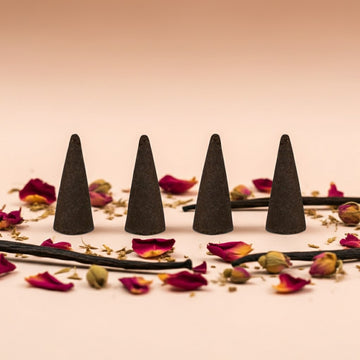 Imported Rose Vanilla Incense Cones on a surface with dried flowers and herbs.