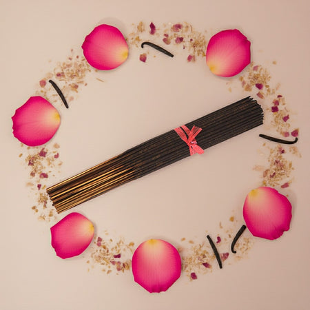 Imported Rose Vanilla Incense Sticks with a pink ribbon surrounded by rose petals on a beige background