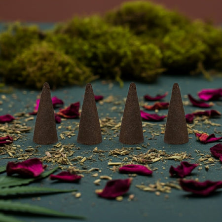 Kush Incense Cones on a dark surface with dried leaves and flowers, against a blurred natural background.