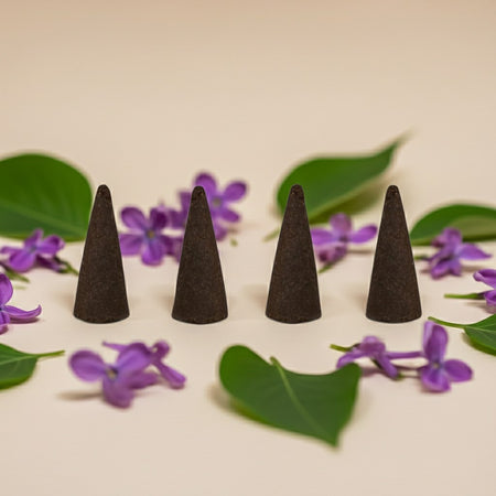 Lilac Incense Cones on a light surface with purple flowers and green leaves.