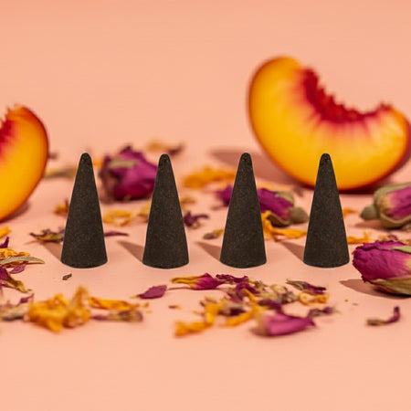 Peach Fantasy Incense Cones on a pink surface with peach slices and flowers.