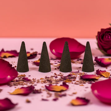 Wet Kisses Incense Cones on a surface with pink petals and a blurred background