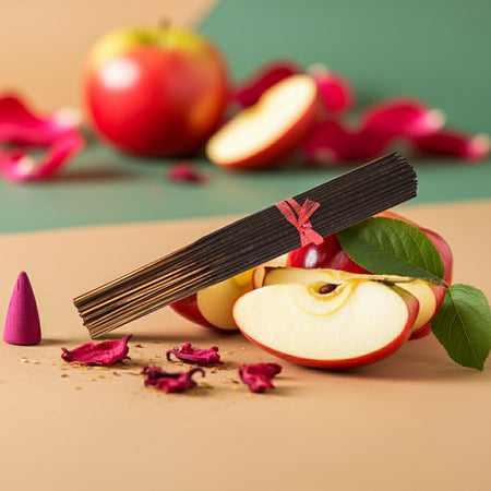 Apple Incense Sticks with a pink ribbon on sliced apples and dried flowers on a beige surface.