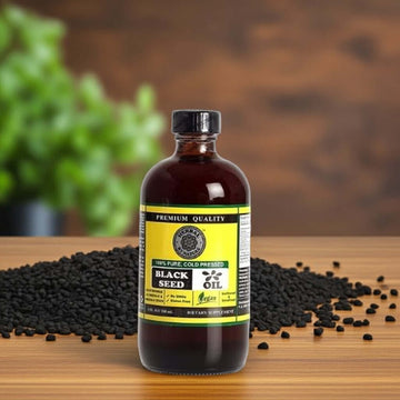 Cold-Pressed Black Seed Oil bottle on wood counter with black cumin seeds