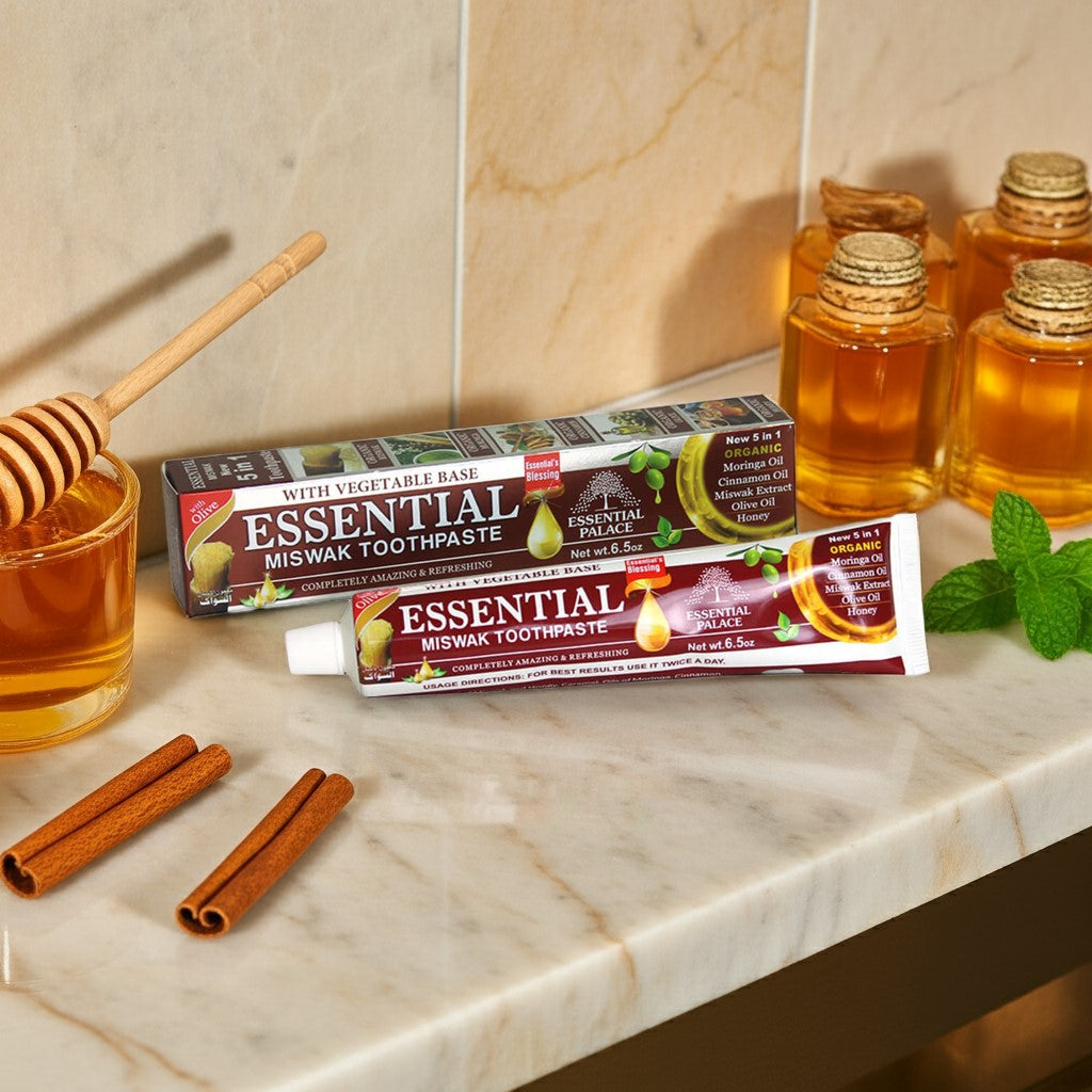 Essential Palace Miswak 5-in-1 Fluoride-Free Toothpaste with miswak sticks, honey, cinnamon, and olive oil on marble counter