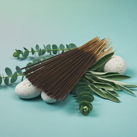 Eucalyptus Incense Sticks with green leaves and stones on a teal background