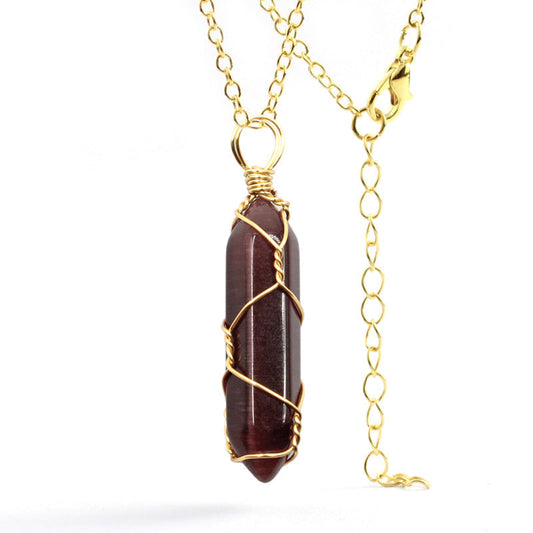 Close-up of a Garnet Necklace featuring a deep red gemstone wrapped in handcrafted gold wire with a stainless steel chain.