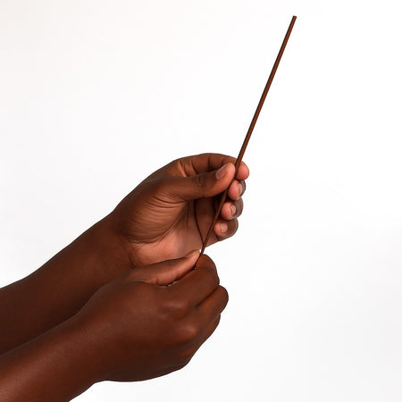 Hand holding Mango Butter Incense Sticks against a white background
