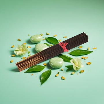 Honeydew Melon Incense Sticks with green stones and flowers on a light green background