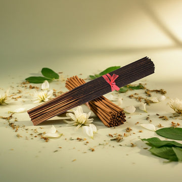 Jasmine Incense Sticks with a pink ribbon on a surface with flowers and leaves