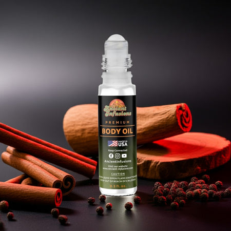 Parfums de Marly Kalan Inspired Body Oil with spicy black pepper and blood orange scent, in a roll-on bottle amidst cinnamon sticks.