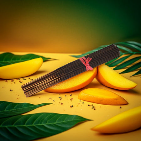 Mango slices and Mango Thieves Incense Sticks on a yellow surface with green leaves