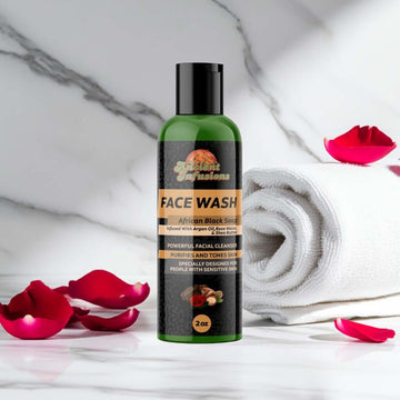 Raw African Black Soap Liquid Face Wash bottle with rose petals and towel on marble surface
