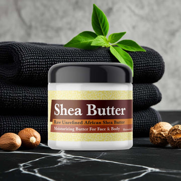 Jar of Tom Ford Noir Inspired Scented Shea Butter on marble with black towels and nuts.