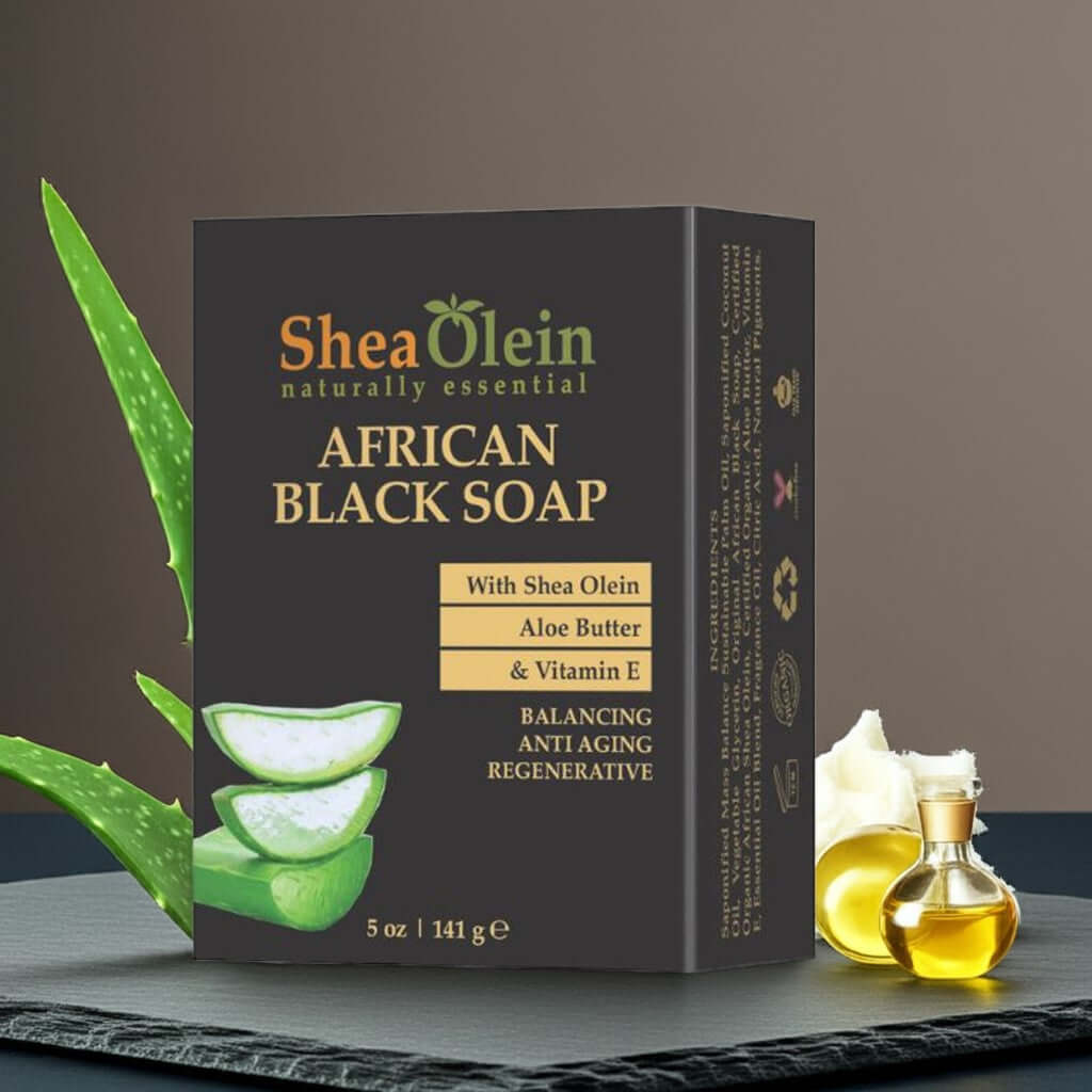 Shea Olein African Black Soap with upright box, aloe slices, shea butter, and vitamin E on slate counter – balancing and anti-aging bar for face and body.